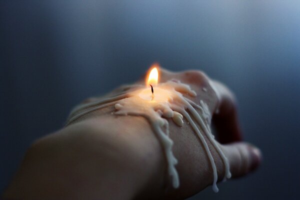 Горящая расплавленная свеча на руке