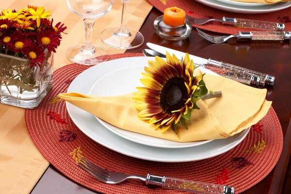 A covered table with a plate on which a napkin and a sunflower