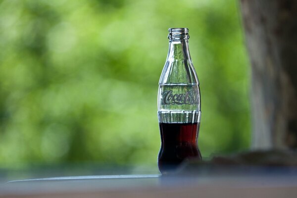 Getränkte Cola-Flasche auf grünem Hintergrund