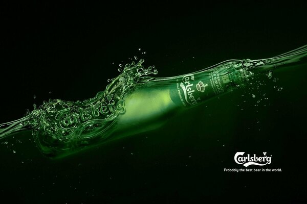 A bottle of carlsberg beer that floats in dark water