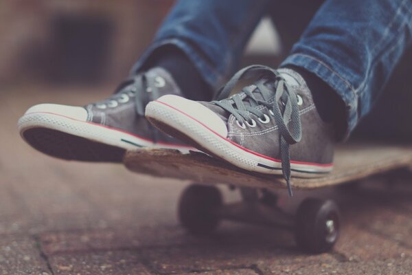 Lo skateboarder mostra la sua tavola e le sue scarpe da ginnastica