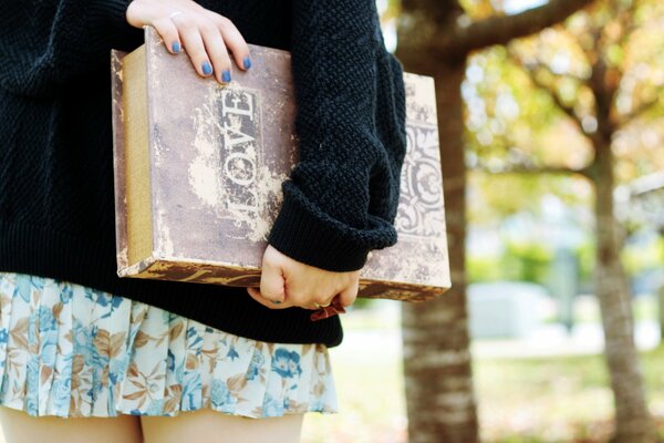 A girl with a Love book with a blue manicure