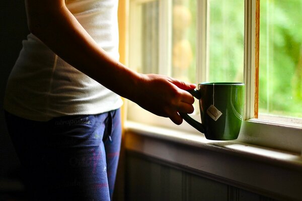 Está de pie junto a la ventana, una taza de té verde en la mano como siempre, y detrás de la ventana, la primavera verde ha llegado