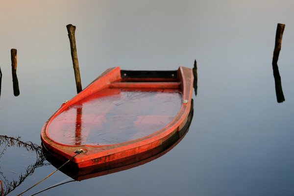 The red boat is tied up in the lake