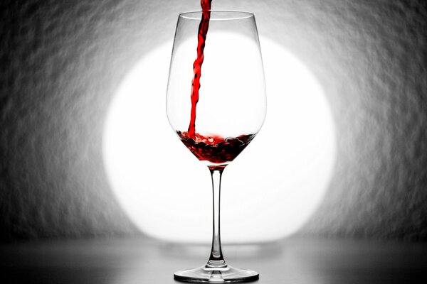 A glass of wine on the background of a gray wall with a light source