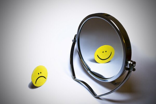 Smiley triste se reflète dans le miroir avec un sourire