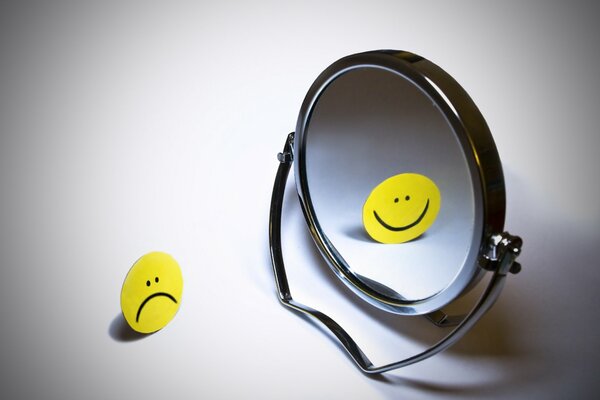Smutna buźka odbija się w lustrze z uśmiechem