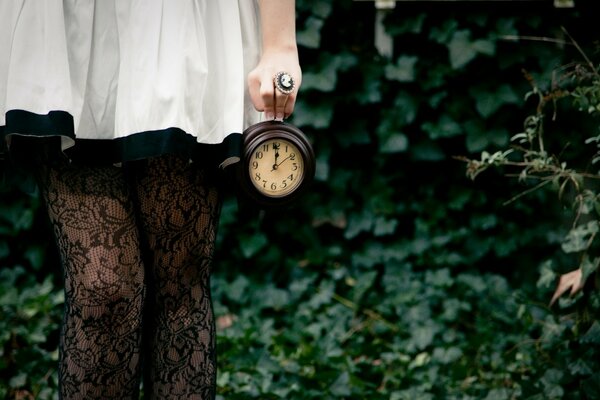 Immagine di una ragazza in un vestito bianco con un orologio in mano