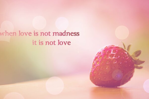 Strawberries on a soft pink background with the inscription When love is not madness it is not love