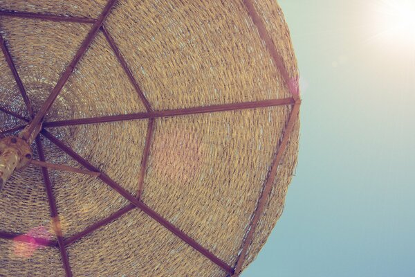 Am Strand unter einem Regenschirm in der Sonne