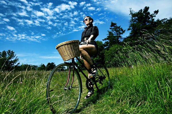 Ragazza con un cestino in bicicletta ai margini della foresta