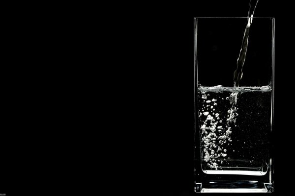 Liquid pouring into a glass on a black background