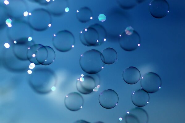 Soap bubbles with glare in the sun. Blue background