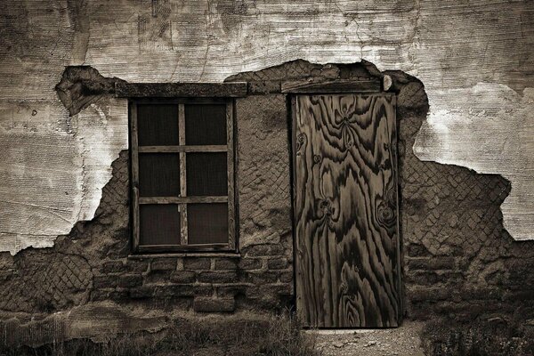 Pared destartalada de una casa antigua con ventana y puerta