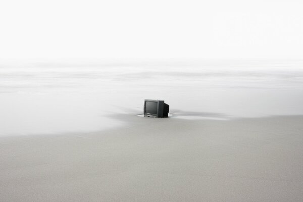 There is a TV on the sea on a deserted beach
