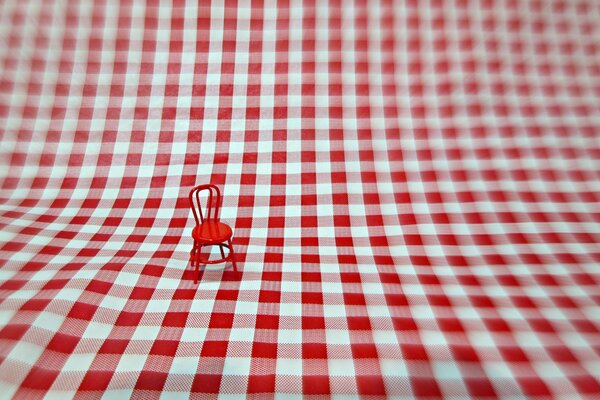 A small red chair on a large canvas in a cage