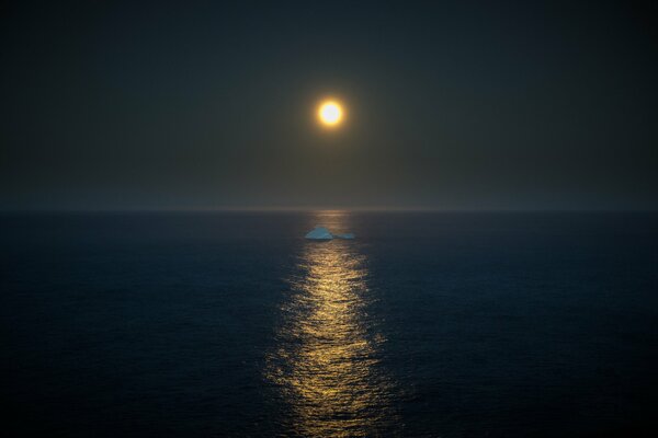 En medio del mar, a la luz de la Luna llena, un iceberg flota