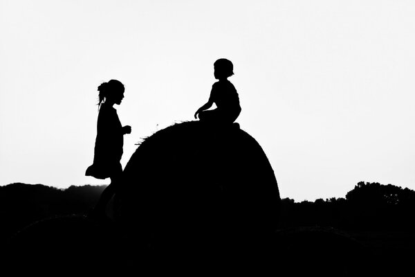 Silhouettes of children on a haystack