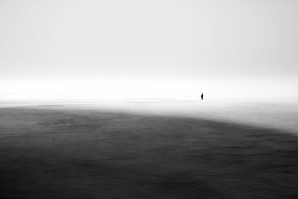Człowiek stojący w morzu we mgle