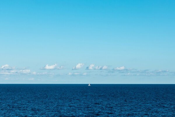 Vela blanca solitaria en la niebla del mar azul