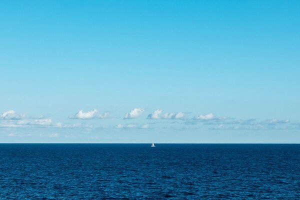 La vela solitaria diventa bianca nella nebbia blu del mare