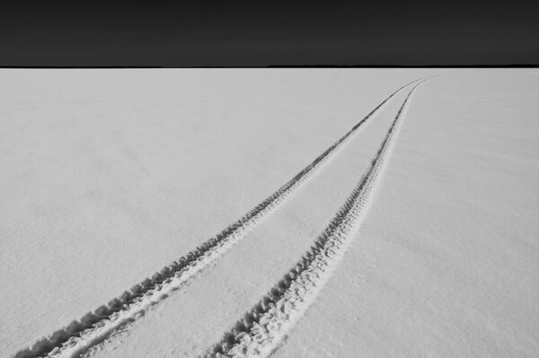 Reifenspuren von einem Schneemobil auf verschneitem Gelände