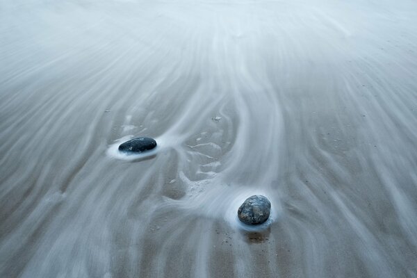 Piedras que yacen en la arena durante el oleaje