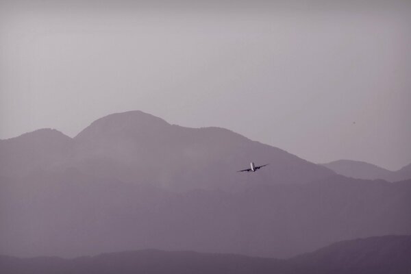 Самолет пролетающий на фоне гор
