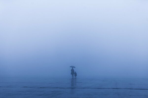 A woman with a child under an umbrella in a storm