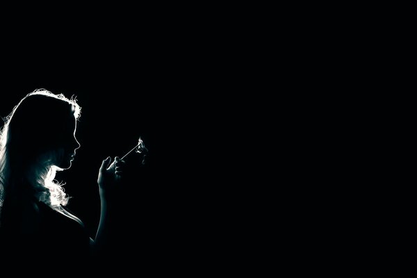 Profil eines Mädchens mit einer Zigarette auf dunklem Hintergrund