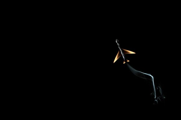 A burning match in the form of an airplane on a black background