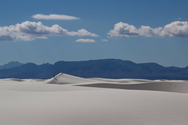 Пустынный пейзаж. Пески и горы на горизонте. Человек идет по пустыне