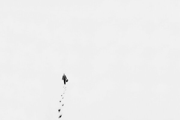 A photo in the style of minimalism taken from high, a man walking in the snow