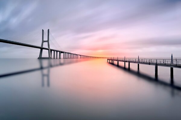 Puentes, superficie de agua, sol de puesta de sol, cielo gris