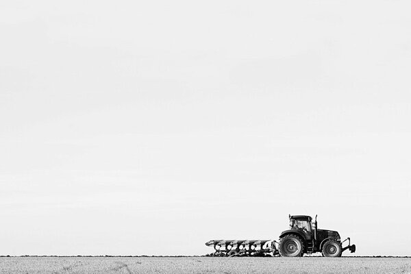 A tractor with a plow rides through the field