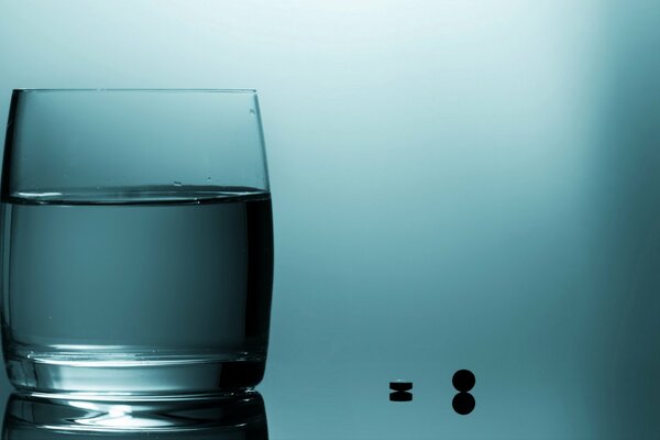 Ein Glas Wasser mit Tabletten auf blau