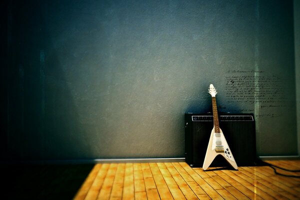 Guitare électrique blanche debout sur le sol près de haut-parleurs