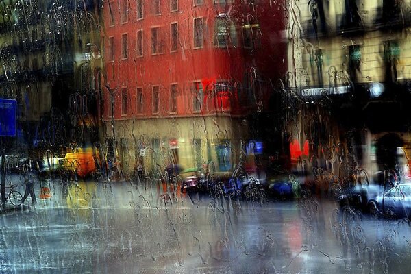 Calle de la ciudad a través de un cristal inundado de lluvia