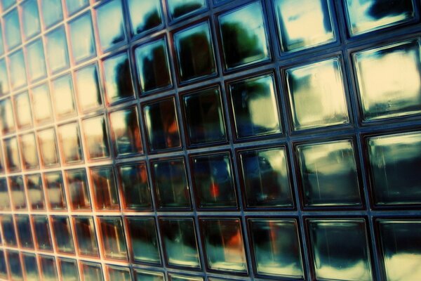 A wall of glass tiles in which something is reflected