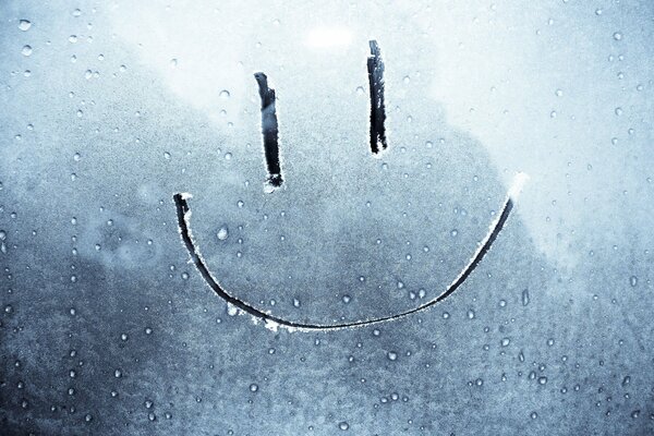 Smiley face painted on glass covered with frost