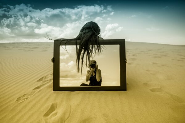 A girl with a mirror in the desert is photographed