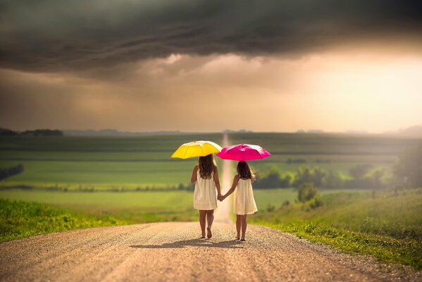 Two girls with umbrellas on the road