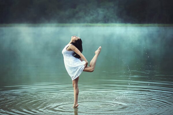 A girl dancing in the water among the fog