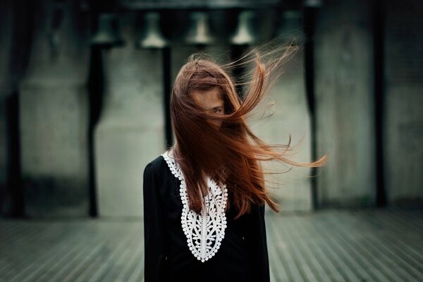Portrait of a girl with her face covered with hair in the wind