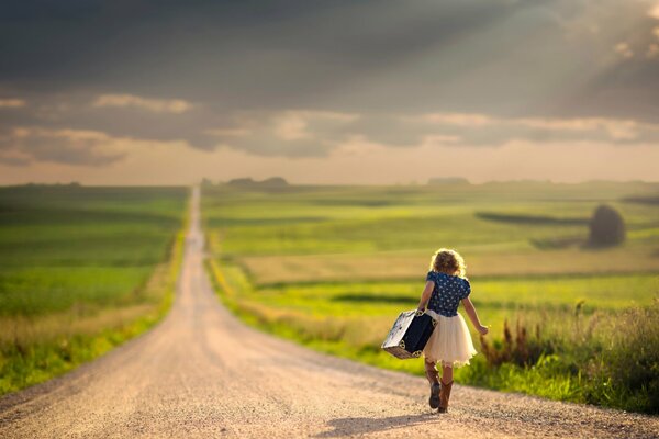 Una ragazza con una valigia che cammina lungo la strada. Strada lunga