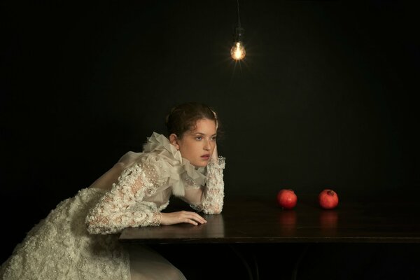 The girl sitting at the table was thinking what to cook from pomegranates