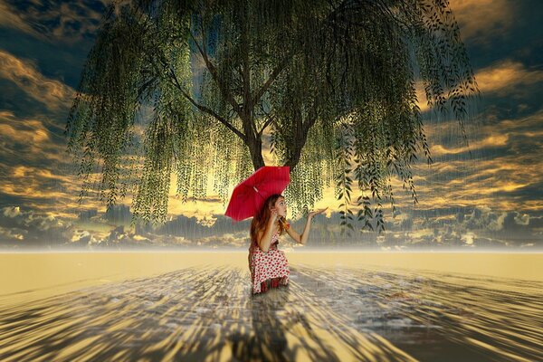 A girl with a red umbrella over a tree in the desert against a cloudy sky