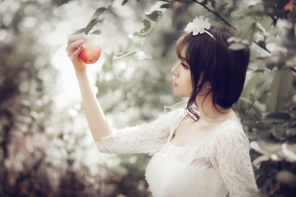 The girl looks at the red apple