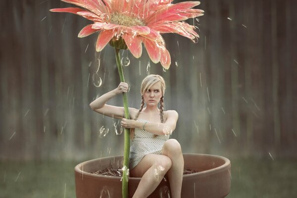 Chica con una flor bajo la lluvia