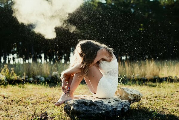 La ragazza in bianco si siede sulla pietra